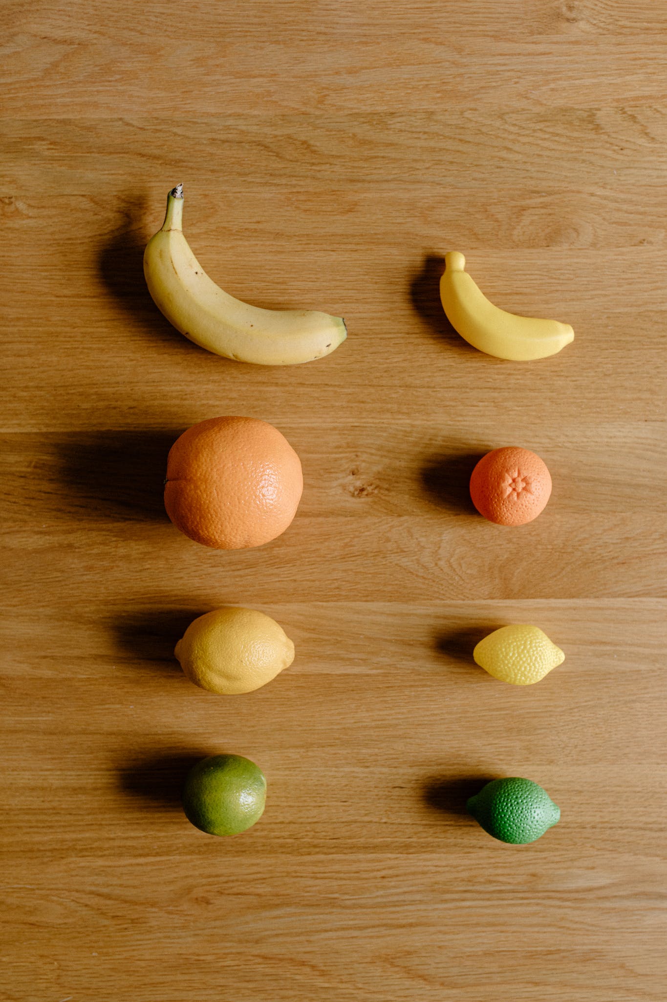 Top view of fresh ripe yellow bananas and oranges near lemons and green limes placed on wooden floor in light room